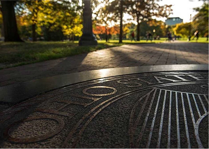 The seal of The Ohio State University stamped into concrete on a pathway.