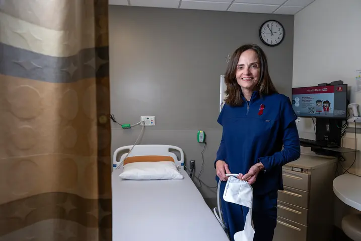 In a hospital room, an oncology nurse gently holds a white towel, appearing focused and composed.