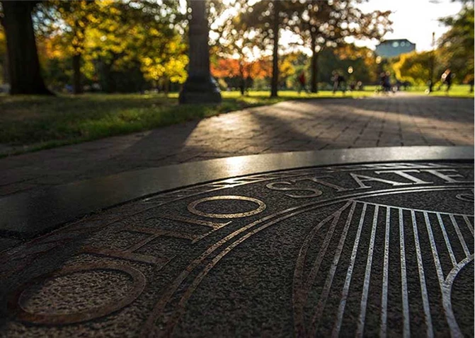 The seal of The Ohio State University stamped into concrete on a pathway.