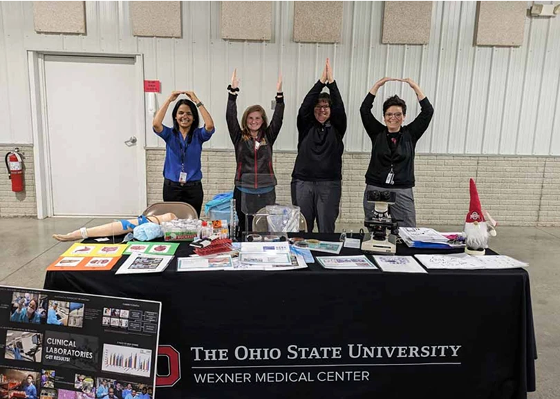 Staff members using their arms to spell out Ohio at a school career event.
