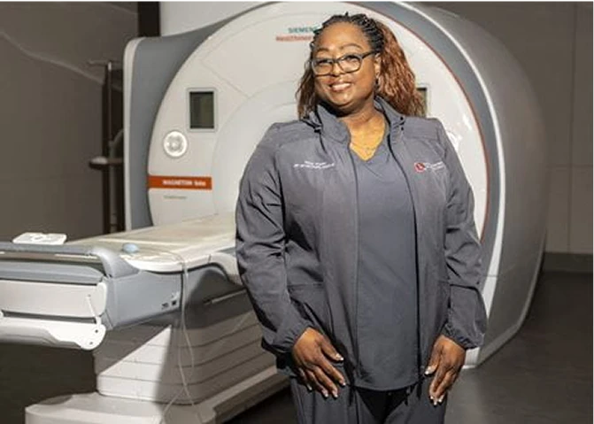 Tracy, an MRI Technologist at OSU Wexner Medical Center, standing in front of an MRI scanner.