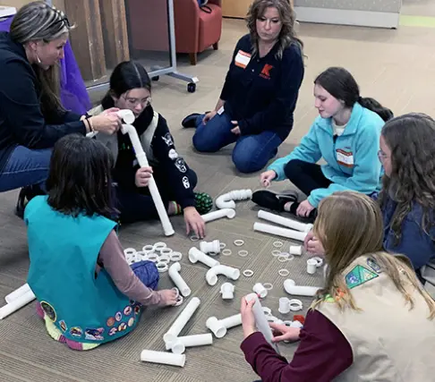 A group of Oatey employees explaining products to a Girl Scout troop.