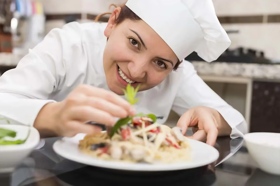 A smiling female cook puts the finishing touches on a delicious salad.
