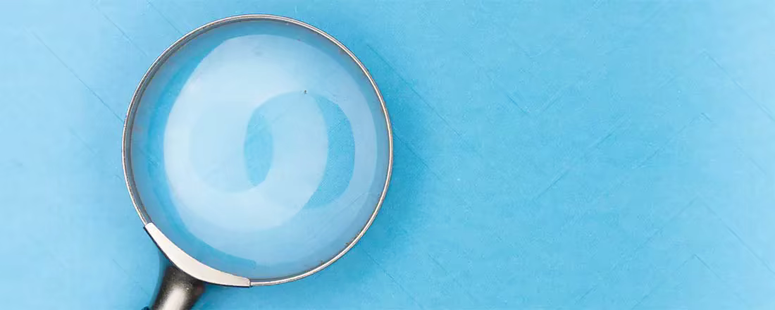 A magnifying glass rests on a blue cloth.