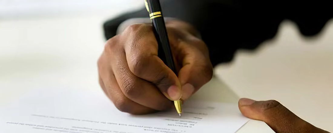 A man's hand holding a pen, ready to complete a job application.