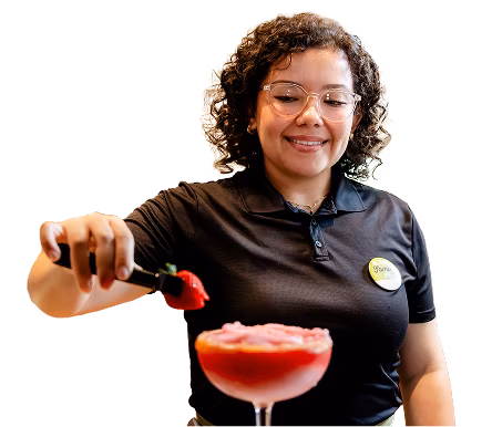 An Olive Garden bartender smiling and making a drink.