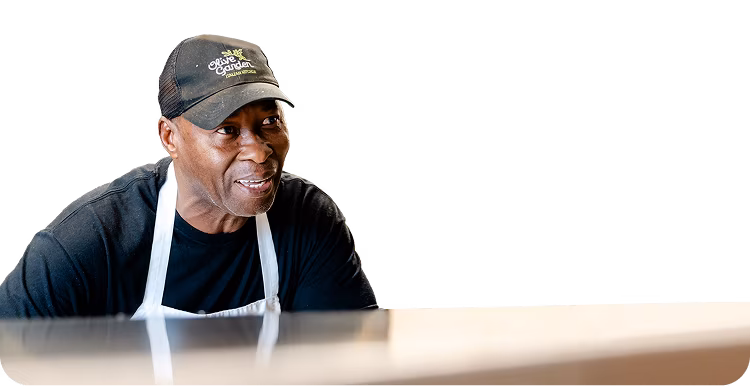 An Olive Garden team member leaning across a counter in conversation while cooking.