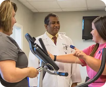Healthcare professional in a white coat observing a patient using exercise equipment