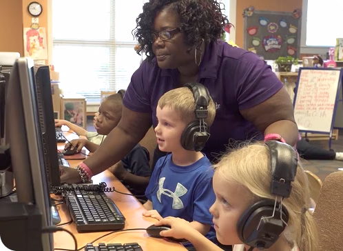 Phoebe employee working with kids on computers in a classroom.
