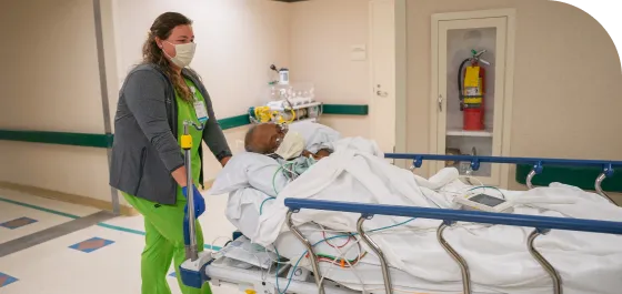 A medical professional wheeling a patient down the hall.