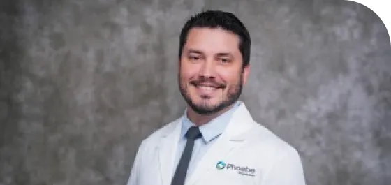 A physician in a white coat, smiling.
