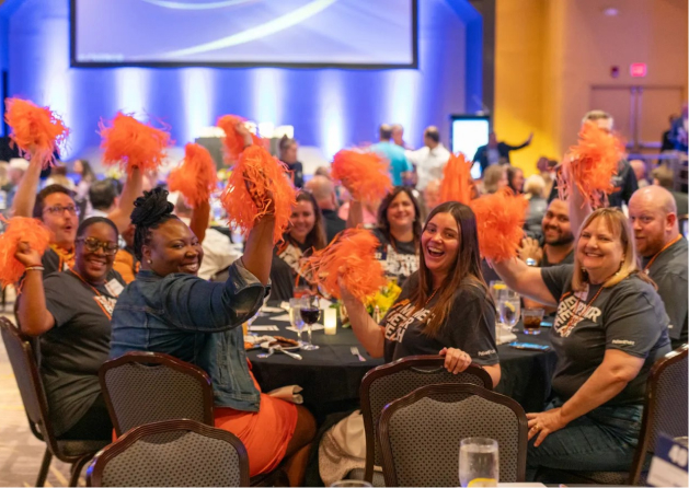 A group of PatientPoint employes sitting around a table celebrating.