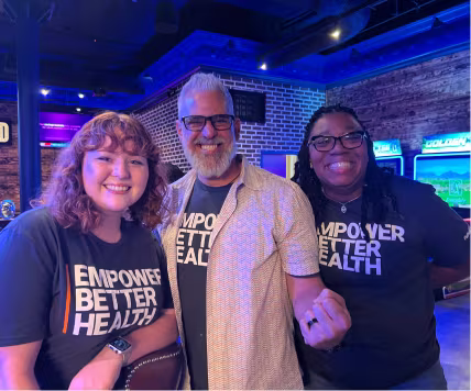 Three PatientPoint employees standing at a team event and smiling.
