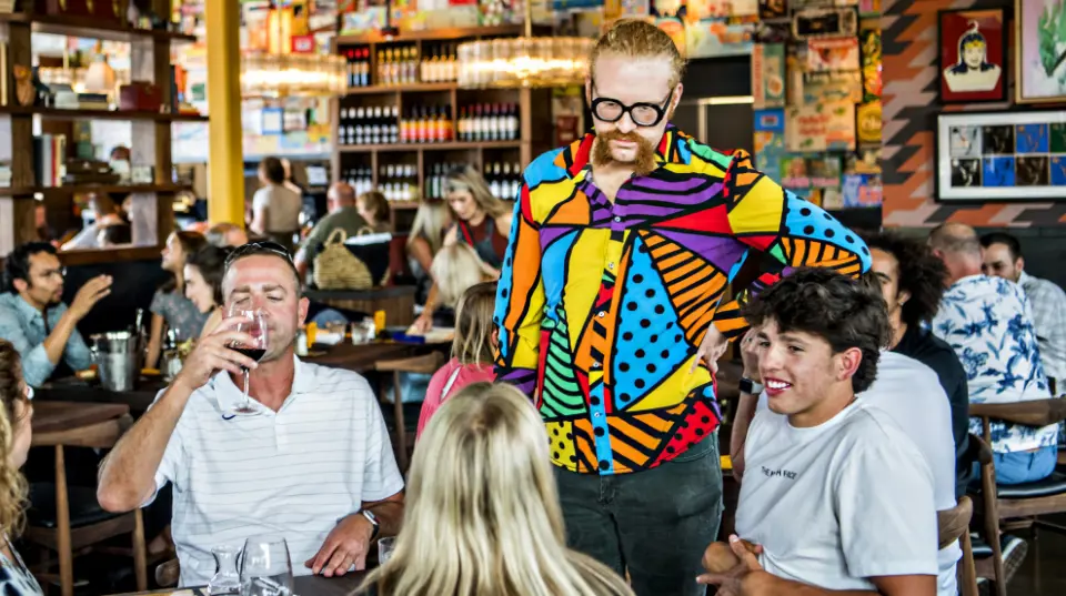  	Postino employee serving wine to patrons.