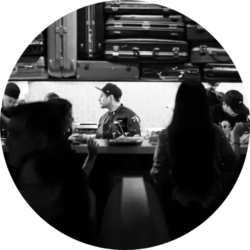 	People sitting at a bar with food.