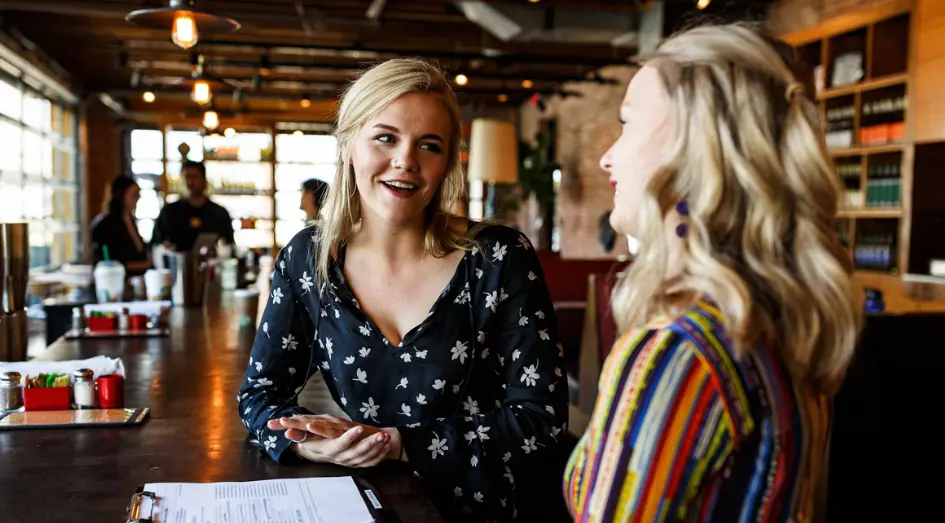 Two Postino employees talking at a bar.