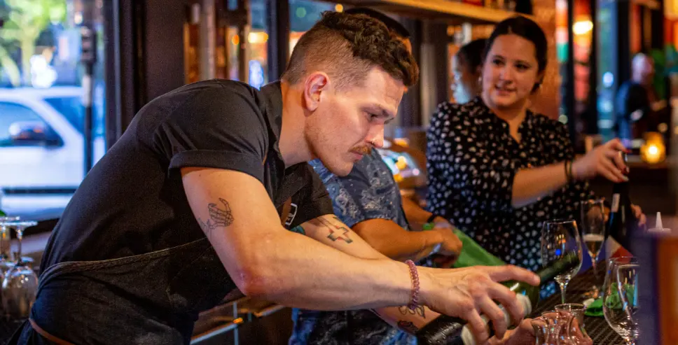 Postino employee pouring a drink.