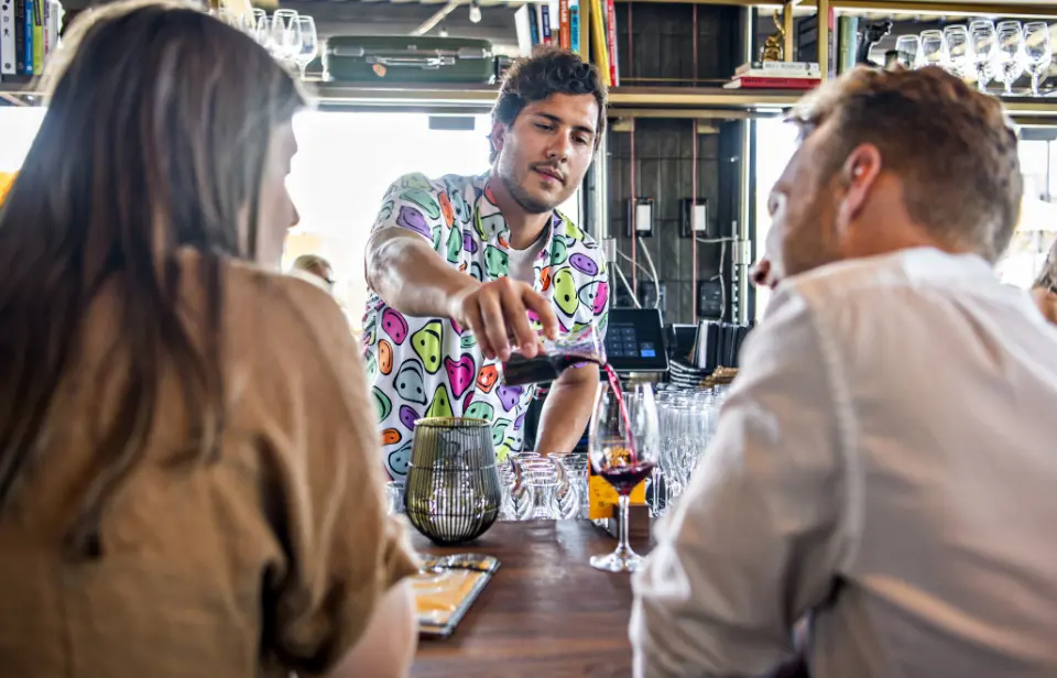 Postino employee pouring a patron a glass of wine.