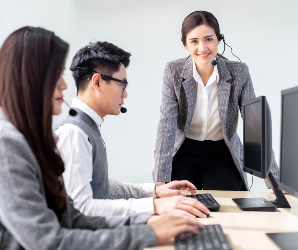 A woman wearing a headset and smiling as she assists other customer service agents.