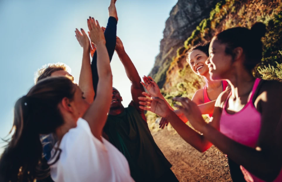 A group high-fiving outside in the sun.
