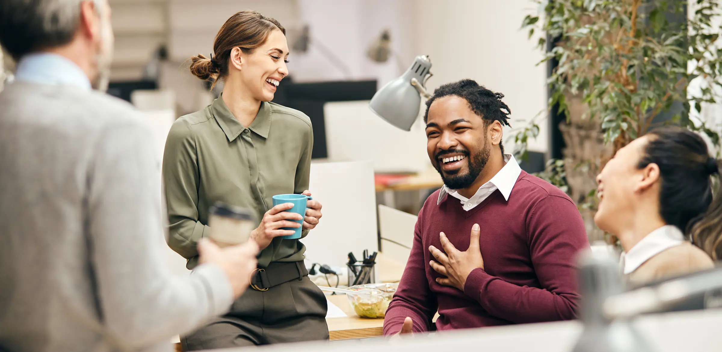 A group of coworkers smiling and laughing as they talk in an office environment.