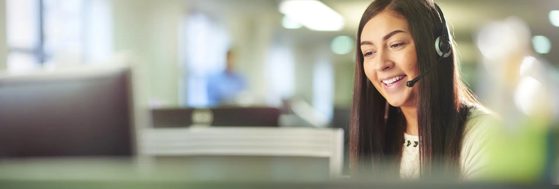 A woman smiling as she makes a call from a headset.