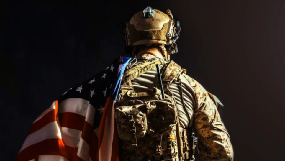 Soldier standing in unifoem with american flag over the shoulder