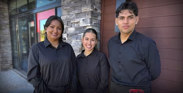 Three Red Lobster team members standing in front of a restaurant and smiling.