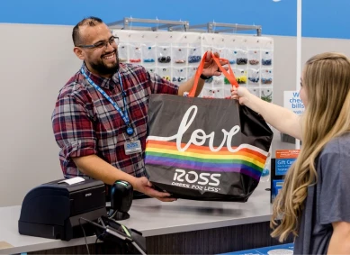 Ross cashier hands a bag to a customer at the checkout