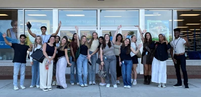 Group of Ross interns waving in front of the headquarters building