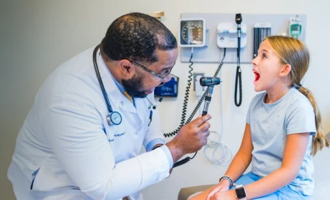 A doctor with a child patient in an exam room.
