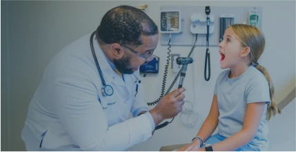 A doctor with a child patient in an examination room.