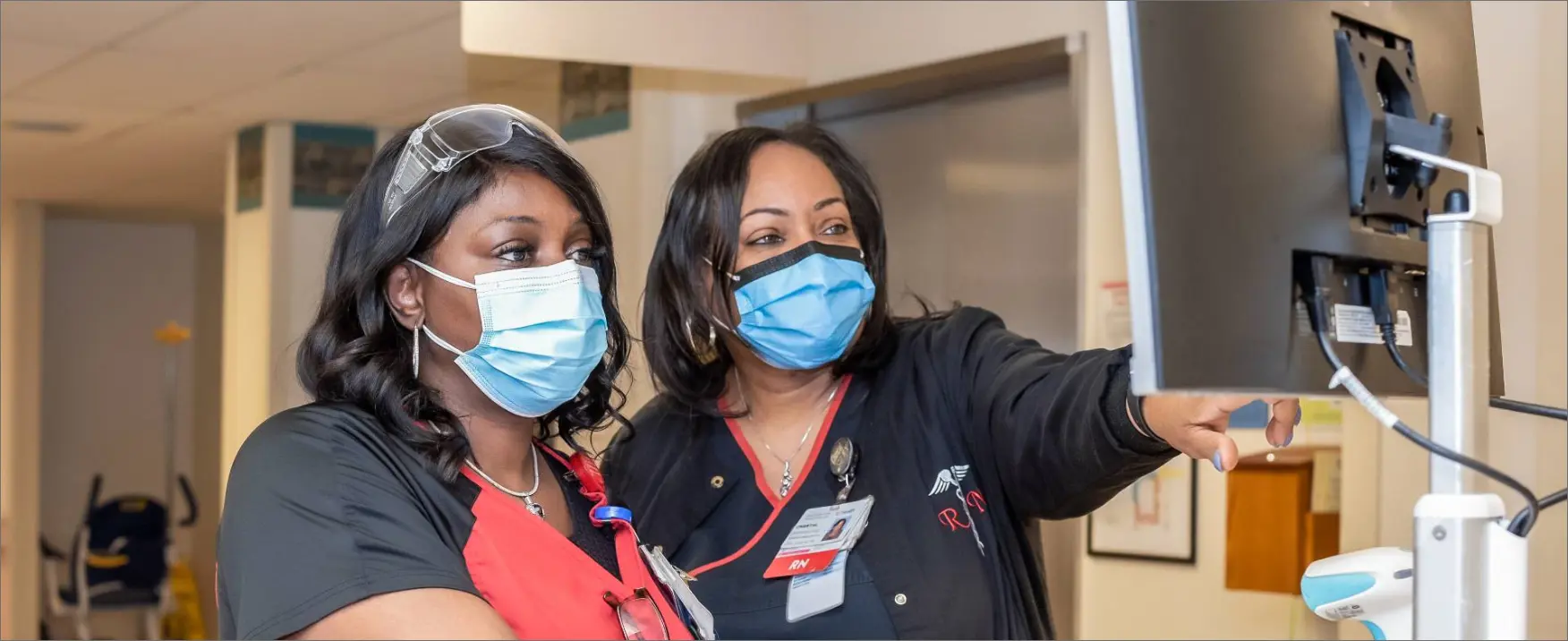  	A female nurse and a nursing manager check a computer screen.