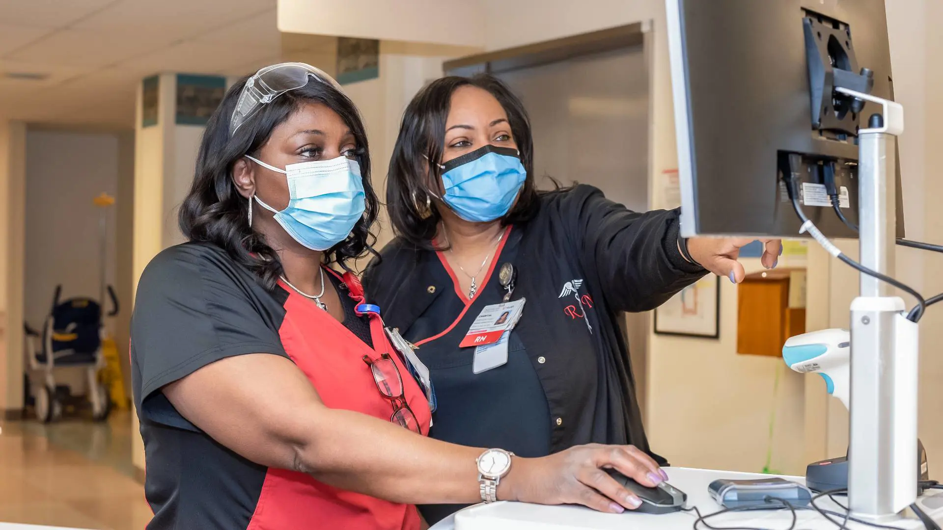  	A female nurse and a nursing manager check a computer screen.