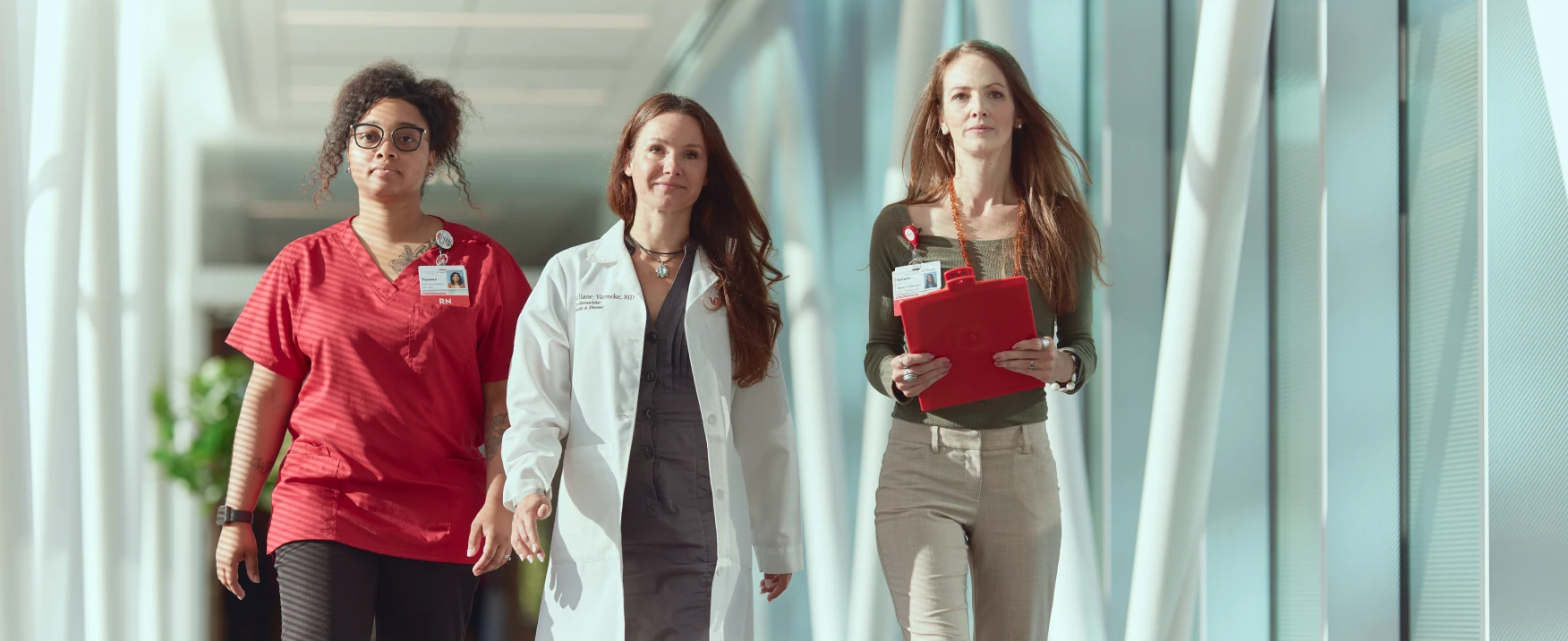 Three UC health team members walking together through a medical facility.