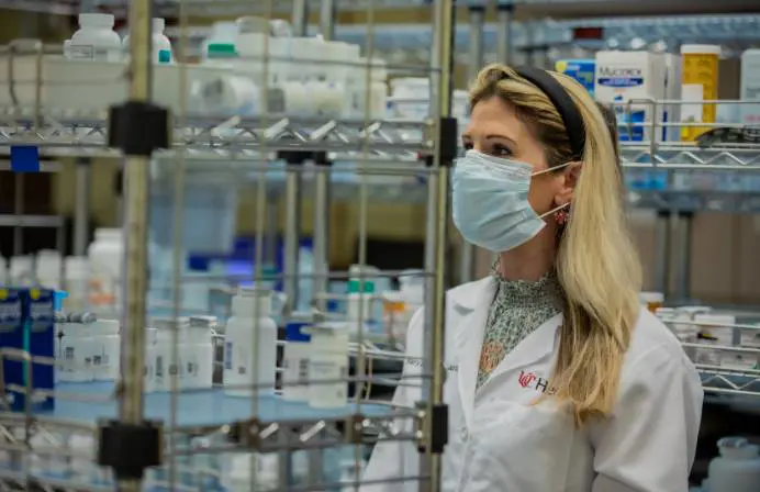 A female pharmacist hands a prescription to a client.