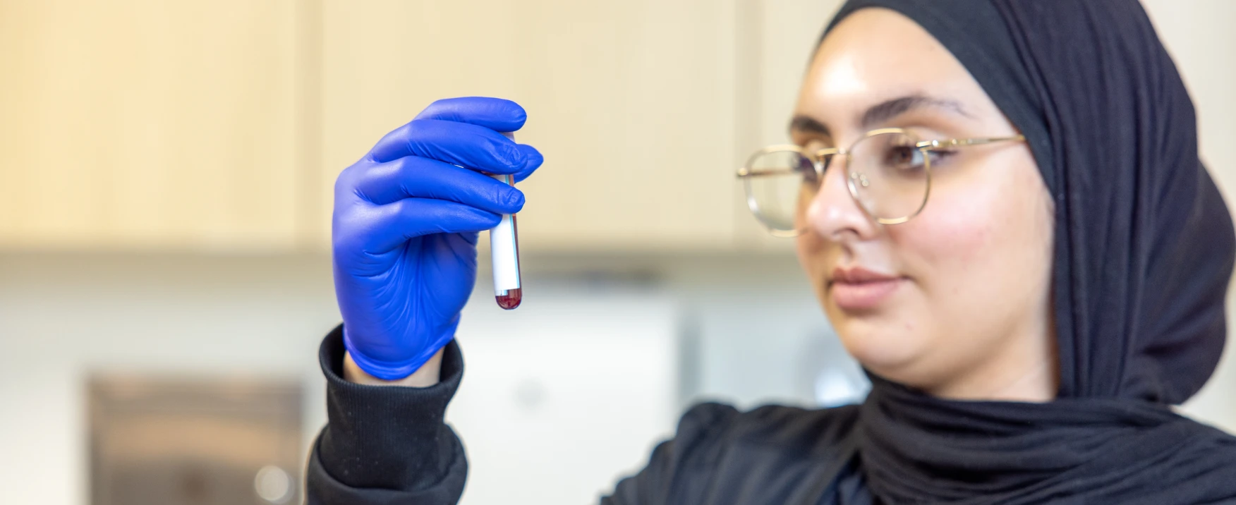 A UC Health team member holding a sample vial.