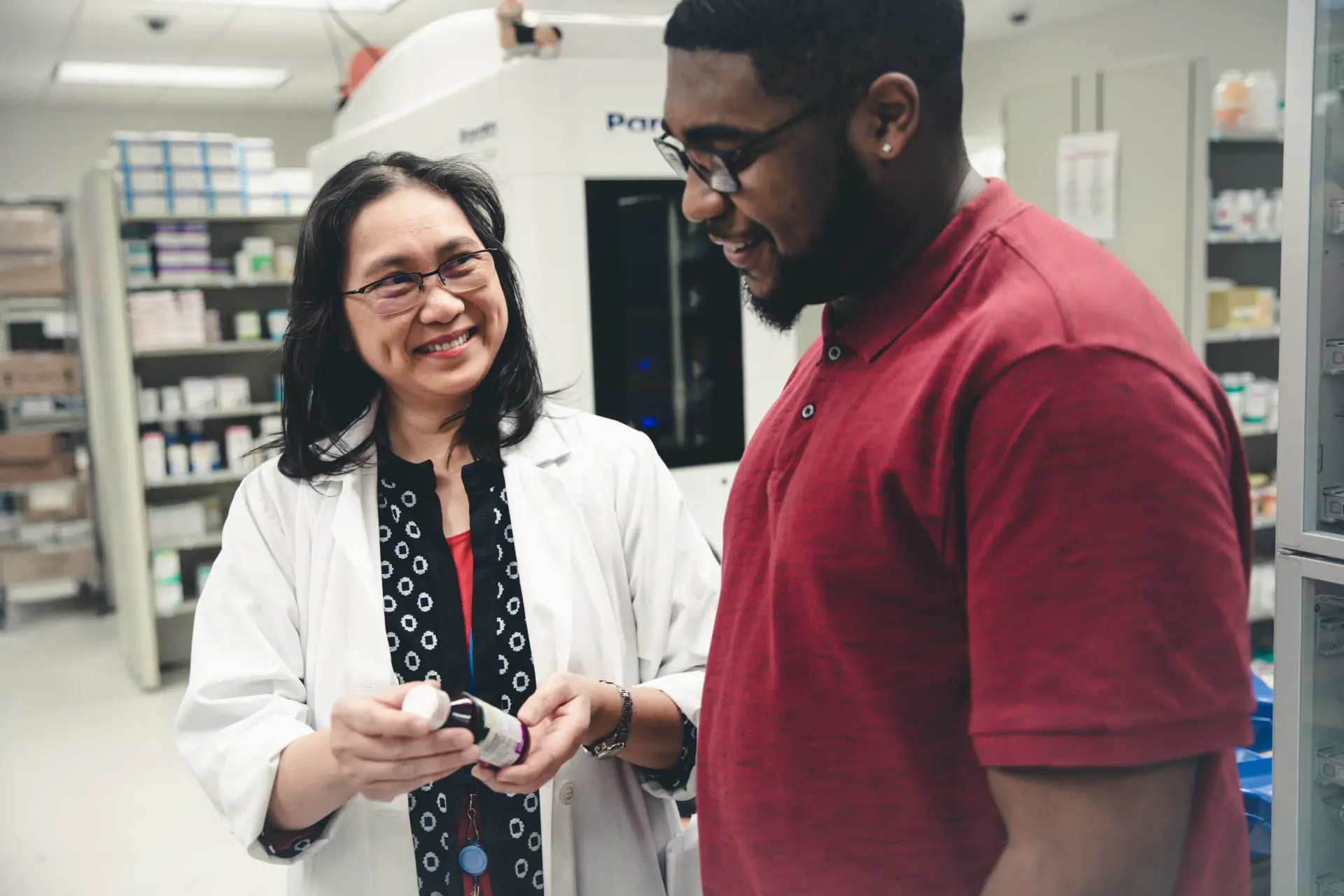  	A female pharmacist hands a prescription to a client.