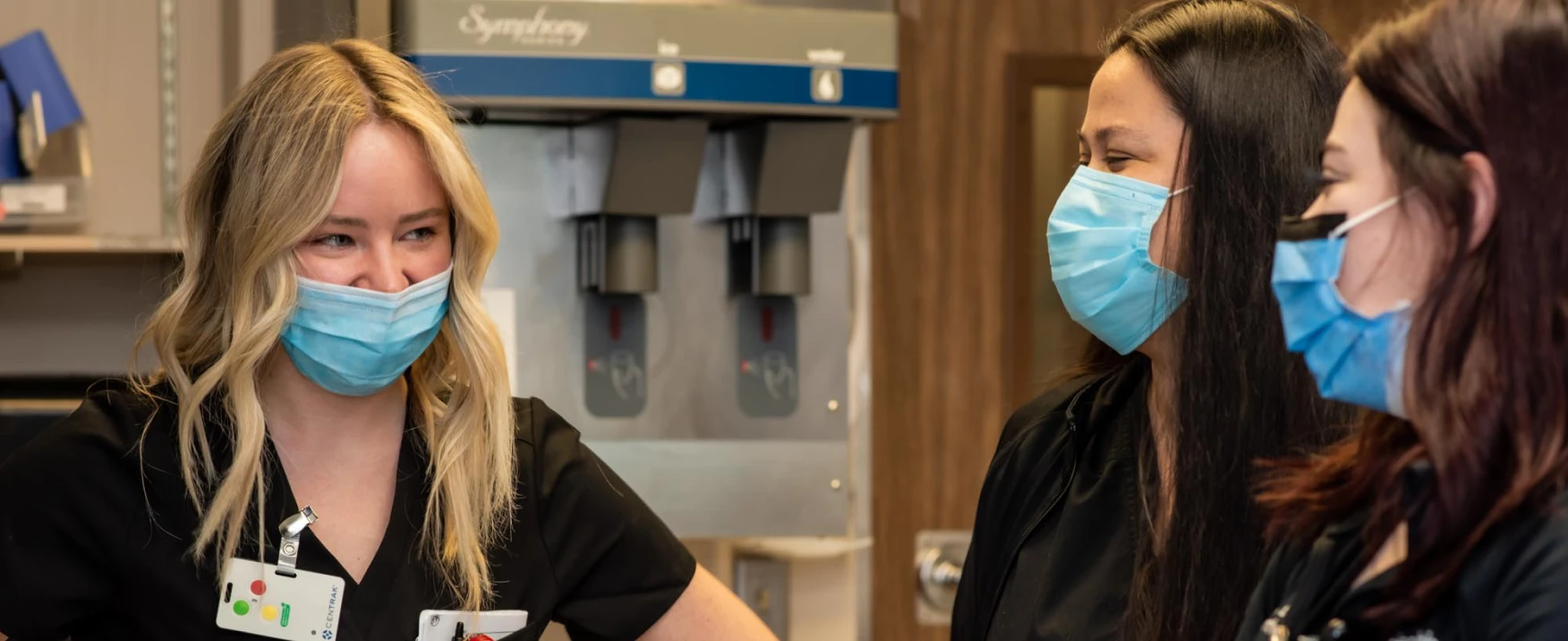 Three UC Health team members smiling and talking.