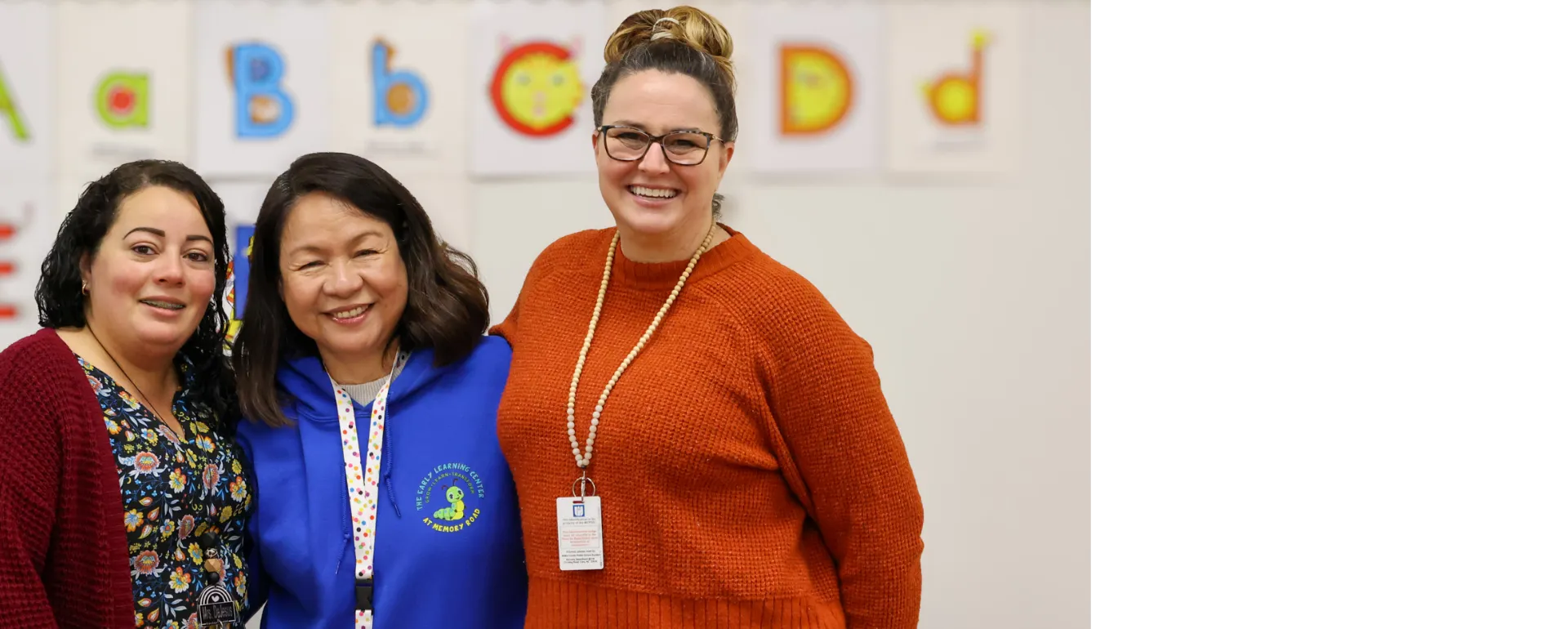 Three educators smiling in a classroom.