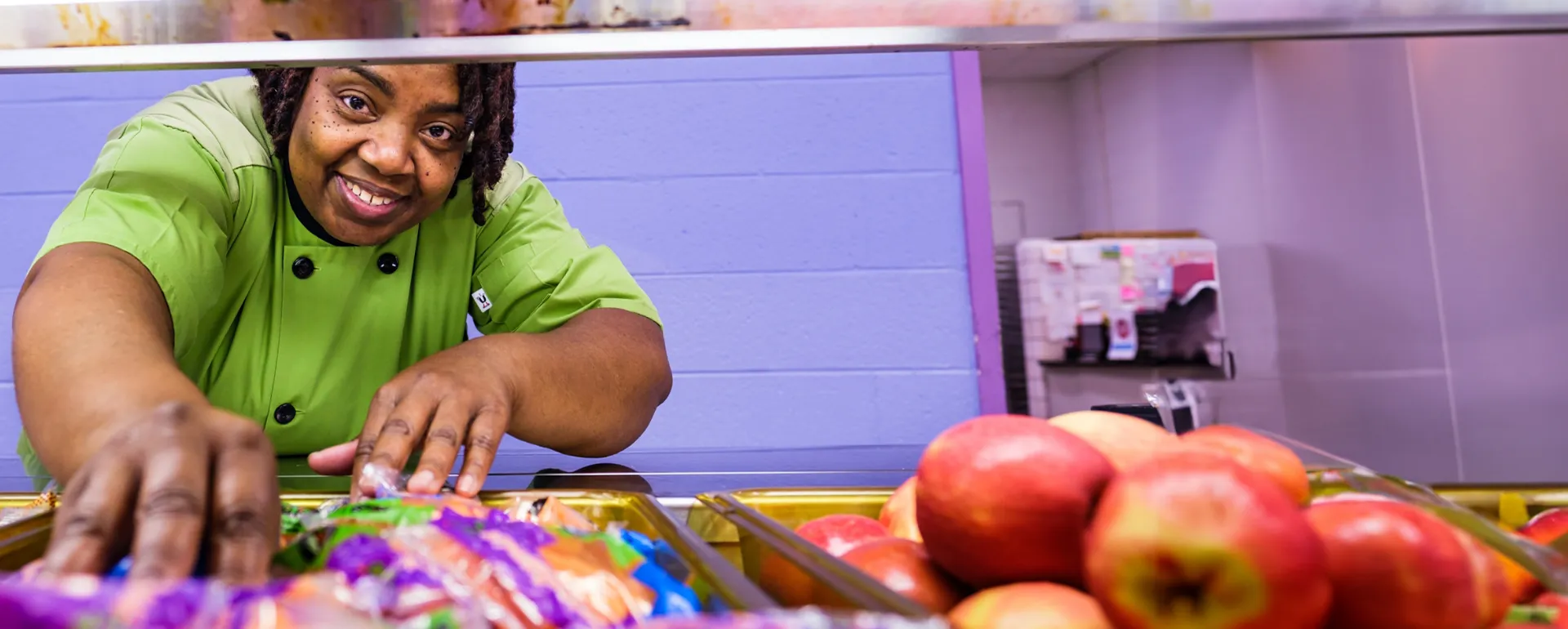 Member of the nutrition services team smiling and serving food.