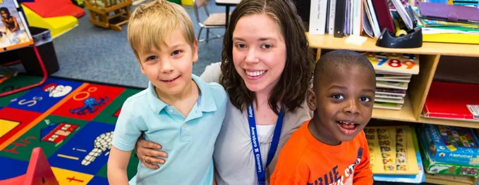 A Special Education Instructional Assistant hugging two students.