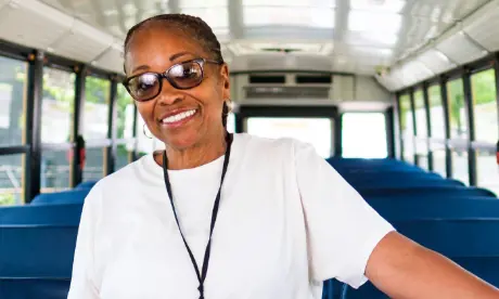 A bus assistant standing and smiling.