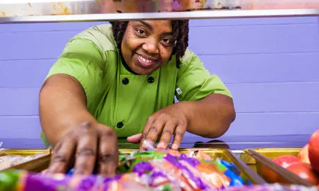 A nutrition services employee serving food.