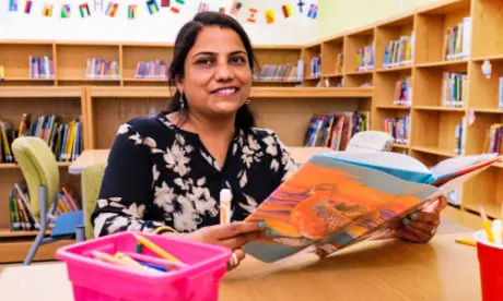 A teacher sitting at a desk and reading.