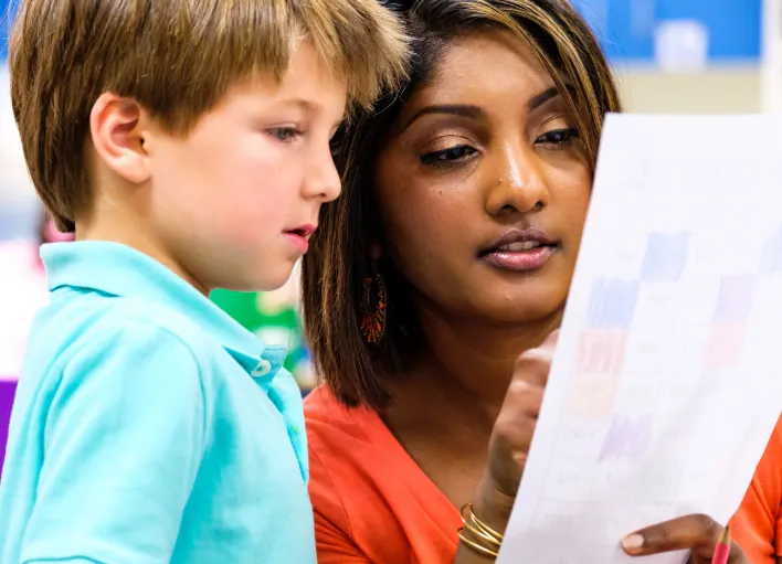 An Instructional Assistant helping a student with an assignment.