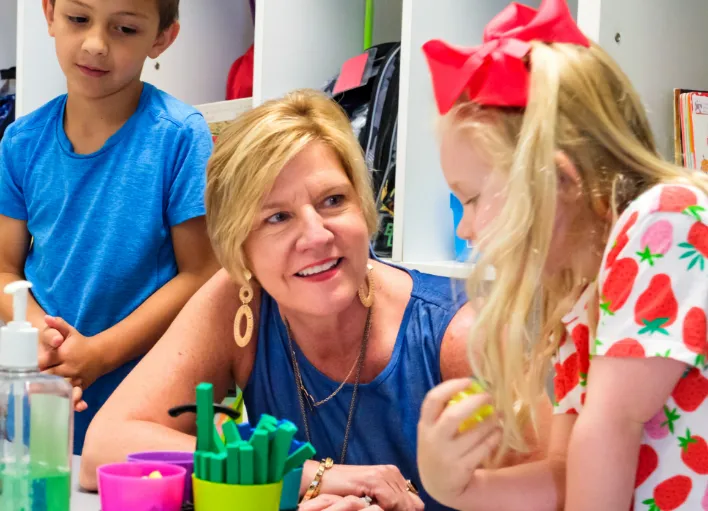 An Instructional Assistant conversing with a student and smiling.