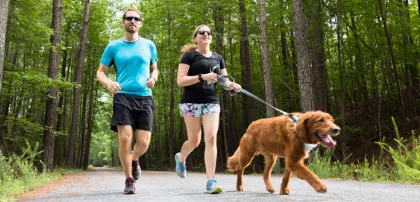 Two educators running on a trail with a dog.