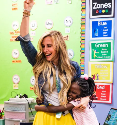 A substitute teacher receiving a hug from a smiling student.