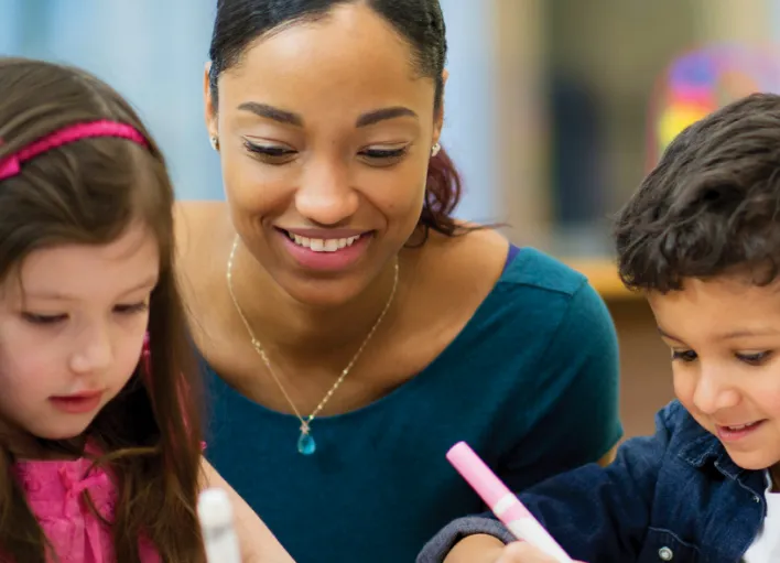 A substitute teacher helping two students with classwork.